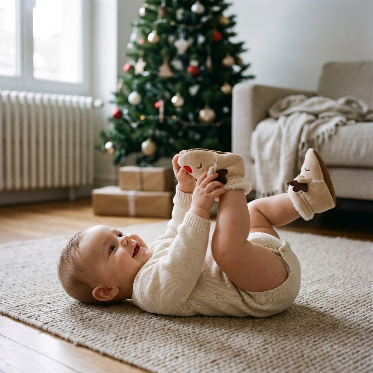 Bébé portant des chaussons de Noël abricot fourrés, au pied du sapin