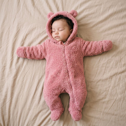 Bébé endormi dans une combinaison bébé polaire peluche rose à capuche ourson