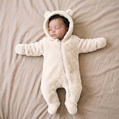 Bébé endormi dans une combinaison bébé polaire peluche blanc lait à capuche ourson